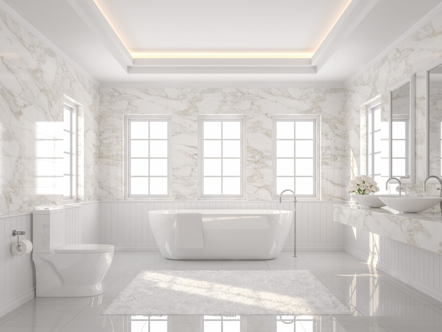 Bright modern bathroom with freestanding tub, toilet, double sinks, and marble walls